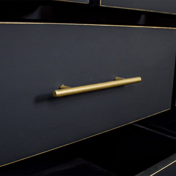 A close up of the gold coloured metal handle on the Cascais Oak Top 7 Drawer Lowboy (Black).