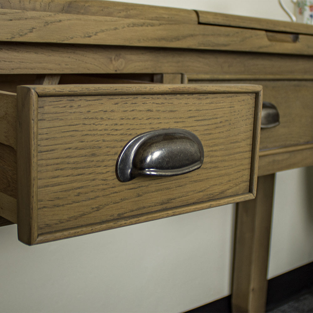 A close up of the brushed silver coloured circular handle on the drawers of the Houston Oak Dressing Table With Mirror.