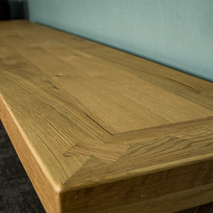 A close up of the top of the Maximus Oak Cross Leg Bench Seat (1.9m), showing the dovetail joining, wood grain and colour.