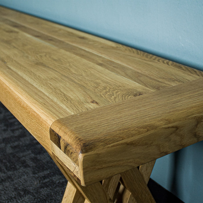 A close up of the top of the Arpege Oak Cross Leg 2m Bench Seat, showing the wood grain.