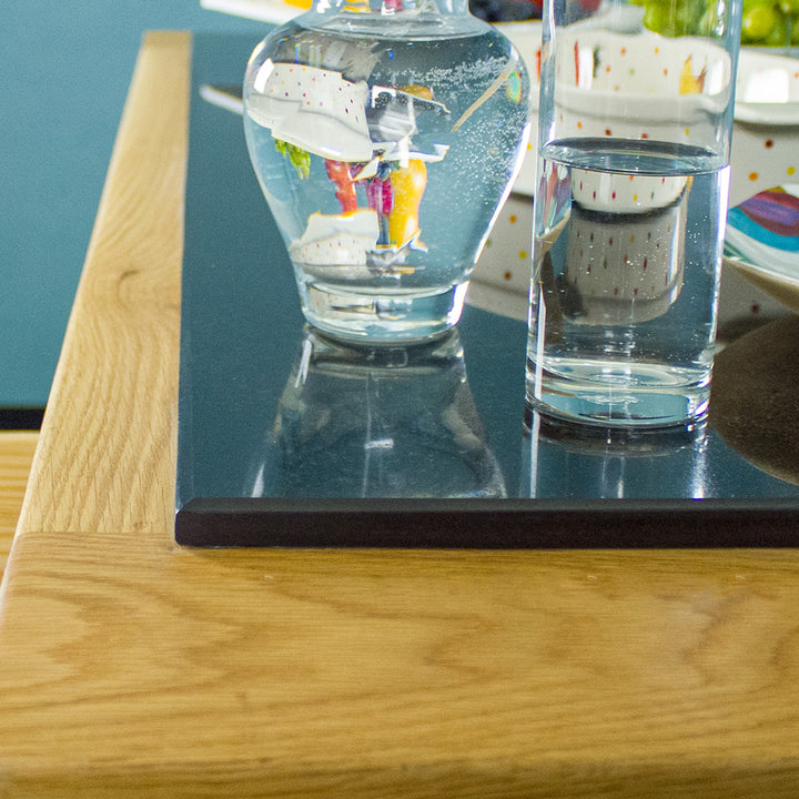 A close up of the granite top of the Danube Large Granite Top Oak Kitchen Island. There is a water pitcher and a glass of water on top. 